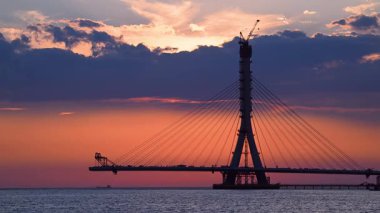 Tamsui, New Taipei City, Tayvan 'daki Danshui Köprüsü' nün devam eden inşaatı güzel bir günbatımının sıcak renkleriyle yıkanır ve çarpıcı bir silüet oluşturur..