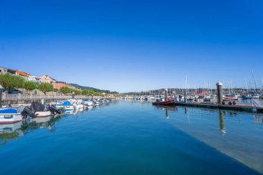 İspanya, Combarro 'daki Baiona Körfezi' nde sakin bir marina. Mavi gökyüzünün altında büyüleyici sahil binalarıyla çevrili tekneleri var..