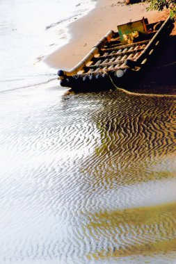 7 Ekim 2012 'de Miaoli County, Tayvan' da gün batımında çekilen dalgalı suyla kumlu bir sahilde bir bambu salı dinlenir..