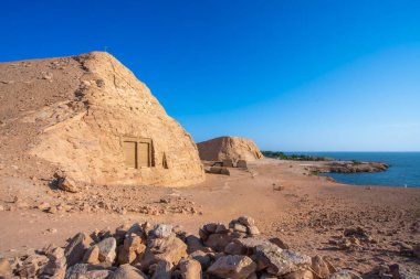 Mısır 'ın Aswan kentindeki Nasser Gölü' nün sakin kıyı şeridi boyunca antik kaya oluşumları ve yapılarıyla büyüleyici çöl manzarası. Bu manzara, muhteşem Abu Simbel Tapınağı 'na giden yol boyunca uzanır..