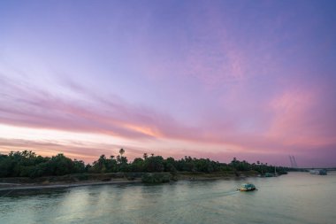 Mısır, Nil 'in Esna Kilidi' nin üzerinde parlak pembe ve turuncu bir alacakaranlık gökyüzü, sakin bir nehirde bir tekne ve bereketli palmiye ağaçlarıyla.