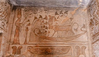 Aswan, Egypt - January 16, 2025: Intricate, well-preserved relief carvings featuring a human figure, boat motif, and hieroglyphs adorn Kom Ombo Temple walls.