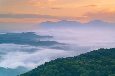 Yuvarlanan sabah sisi ve bulutları, Shulin İlçesi 'nin Yeni Taipei Şehri Tayvan dağlarını yüksek voltajlı güç kuleleri ve sislerin arasından beliren sönük bina siluetleri ile kaplıyor..