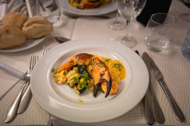 Sintra, Portekiz - 8 Mart 2025: Resmi giyinmiş garsonlar sıcak bir restoranda midye ve balık ile buharlı deniz ürünleri yahnisi servis ediyorlar. Yerel aşçılık uzmanlığını ve yemek atmosferini yansıtıyor.