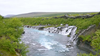 Yaz boyunca İzlanda 'daki Hraunfossar şelalelerinin yavaş çekim görüntüleri. Turkuaz buzul suyu antik lav oluşumlarının üzerinden akar ve eşsiz bir doğal mucize yaratır..