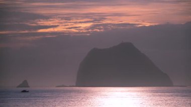 Keelung Adası 'nda büyüleyici bir gün doğumu ve Tayvan Waimushan' da bir balıkçı teknesi. Gökyüzü turuncu ve altın sarısı rüya gibi renklerle boyanır. Huzurlu ve resimsel bir manzara yaratır..