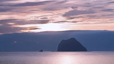 Güneş denizin üzerinde yükseliyor, Keelung Adası ve Tayvan 'ın Keelung kentindeki Waimushan kıyı şeridi yakınlarındaki Little Keelung Adası' na altın bir ışık tutuyor..