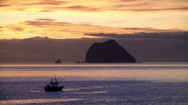 Keelung, Tayvan 'daki Waimushan kıyı şeridinde görkemli bir gün doğumu. Arka planda Keelung adası olan bir balıkçı teknesi denize karşı yüzer..