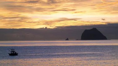 Waimushan, Keelung, Tayvan 'da çarpıcı bir yaz gündoğumu yaşayın. Büyük ve Küçük Keelung yakınlarındaki balıkçı teknelerini seyret Turuncu ve altın bir gökyüzünün altında.