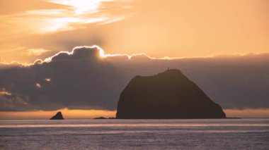 Güneşin Keelung Adası ve ikonik deniz fenerinin üzerinden doğuşunun çarpıcı bir videosu. Keelung Tayvan 'daki Waishuangxi Sahili' nden çekilen gökyüzü altın bir parıltıyla dolu..