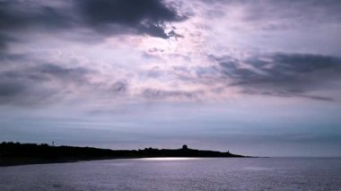 New Taipei City Tayvan 'daki Shimen Sahili' nde çekilmiş güzel bir deniz manzarası. Güneş ışınları çarpıcı bulutları delip geçer ve çarpıcı bir yansımayla okyanusu aydınlatır..