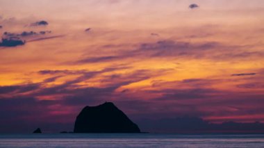 Keelung Adası üzerinde çarpıcı bir gün doğumu dramatik turuncu gökyüzü bulutlarıyla balıkçı tekneleri siluetleri huzurlu okyanus dalgaları yaz sabahı.