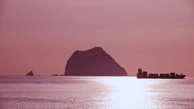 Waishuangxi, Tayvan 'da Keelung Islets yakınlarında hareket eden bir kargo gemisinin siluetini görün. 23 Haziran 2025 'te sakin bir yaz sabahı çekildi..