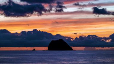 Güneş doğarken turuncu ve kırmızı gökyüzünde hızla hareket eden kara bulutlar Keelung Adası ve Waimushan plajı Tayvan 'da..
