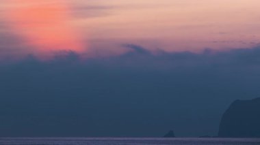 Keelung Waimushan, Tayvan 'da güzel bir şafak. Gökyüzü turuncu ve mavinin yumuşak neon renkleriyle aydınlanır, sakin denizin üzerinde sakin ve dingin bir atmosfer yaratır..