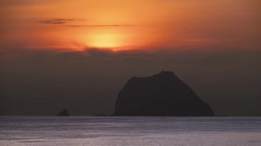 Güneş kara bulutların ardından yükselirken Tayvan 'ın başkenti Keelung Waimushan' da Jilong Adası 'nın siluetine tanık olun. 2025 'te çekilmiş..