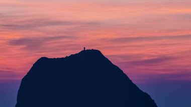 Waimushan Tayvan 'dan görülen Keelung Adası üzerinde şafak öncesi gökyüzü, pembe ve mor bulut bantları ve sakin denizin üzerinde karanlık bir ada silueti.