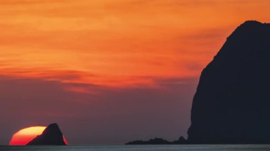 Waimushan Beach Keelung Tayvan 'da muhteşem bir gün doğumu. Altın güneş Keelung Adası 'nın arkasından yükseliyor. Deniz feneri, sakin okyanus üzerinde dramatik turuncu bir gökyüzü oluşturuyor..