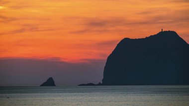 Waimushan Tayvan 'dan Keelung adası üzerinde gün doğumu, ılık turuncu ve mavi neon bulutlar sakin bir yaz denizi üzerinde.