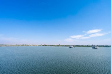 Nil Nehri 'nin geniş panoramik manzarası Esna yakınlarındaki gemi ve köprü ile Mısır' ı güzel mavi gökyüzünün altında beyaz bulutlarla kilitle.