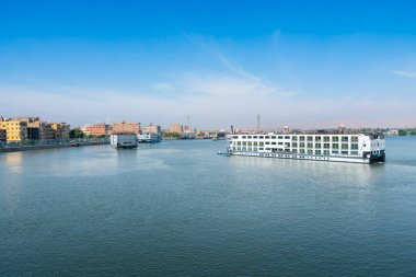Çoklu Nil Nehri seyahat gemileri durgun sularda geziniyor, şehrin şehir manzarası ile Esna Kilidi 'ne yaklaşıyorlar berrak mavi bir gökyüzünün altında nehir kıyısı boyunca görülebilir..
