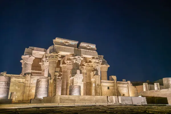 Muhteşem Kom Ombo Tapınağı geceleri karanlık bir gökyüzüne karşı aydınlanır. Antik sütunlarını ve güçlü yapısını aydınlatır..