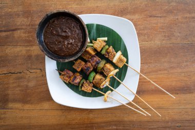Top down view of vegan satay skewer with tofu and tempeh with peanut sauce, horizontal