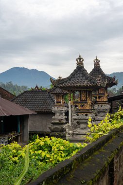 View of traditional Balinese temple with mountains in the background, vertical