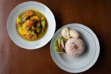 Top down view of a Sayur Kare (Balinese Vegetable Curry) on white plate with rice, horizontal