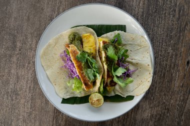 Top down view of mexican tacos with grilled Halloumi cheese and pineapple, salsa verde and coriander