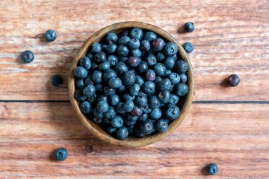 Top down view of a bowl of fresh blueberries on wooden background, horizontal, copyspace