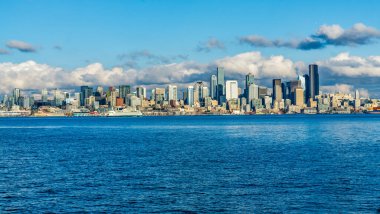 Seattle siluetinin mimarisi. Önünde Elliott Körfezi, üstünde bulutlar var. Sahnede bir feribot da var..