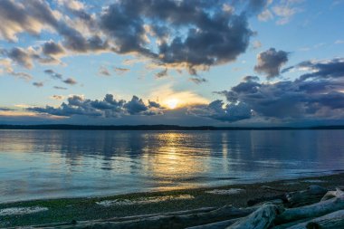 Batı Seattle, Washington 'daki Lincoln Park' ta güneş bulutlu bir havada batıyor..