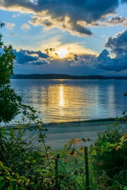 Batı Seattle, Washington 'daki Lincoln Park' ta güneş bulutlu bir havada batıyor..