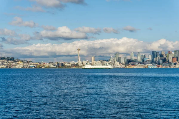 stock image Architecture of the Seattle skyline with Elliott Bay in front and clouds above. A ferry is also in the scene.