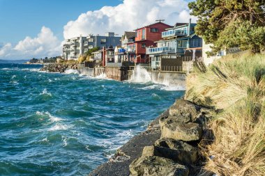 Waves on a windy day hit the shoreline near waterfront homes in West Seattel, Washington.