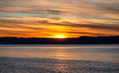 Puget Sound 'da batan güneşin çevresindeki zengin renkler. Fotoğraf Burien, Washington 'daki Seahurst Sahili' nden çekildi..