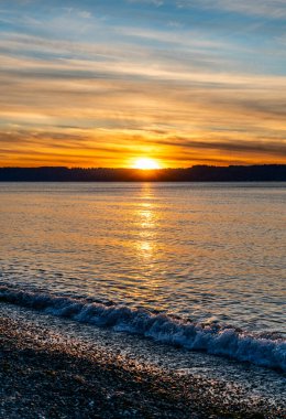 Puget Sound 'da batan güneşin çevresindeki zengin renkler. Fotoğraf Burien, Washington 'daki Seahurst Sahili' nden çekildi..