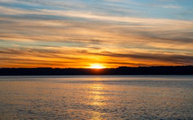 Puget Sound 'da batan güneşin çevresindeki zengin renkler. Fotoğraf Burien, Washington 'daki Seahurst Sahili' nden çekildi..