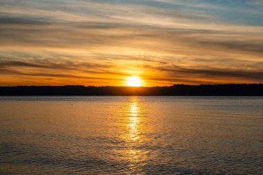Puget Sound 'da batan güneşin çevresindeki zengin renkler. Fotoğraf Burien, Washington 'daki Seahurst Sahili' nden çekildi..