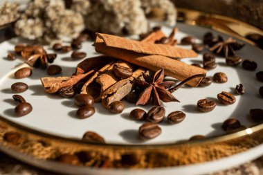 Altın bir tabakta tarçın ve anason, kahve çekirdekleri ve çuval bezi. Sert doku ve baharat kompozisyonu. Kurumuş çiçeklerle. Şekerleme, fırın ve Noel kartlarında kullanılıyor.