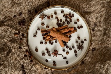 Altın bir tabakta tarçın ve anason, kahve çekirdekleri ve çuval bezi. Sert doku ve baharat kompozisyonu. Kurumuş çiçeklerle. Şekerleme, fırın ve Noel kartlarında kullanılıyor.