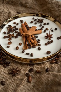 Altın bir tabakta tarçın ve anason, kahve çekirdekleri ve çuval bezi. Sert doku ve baharat kompozisyonu. Kurumuş çiçeklerle. Şekerleme, fırın ve Noel kartlarında kullanılıyor.