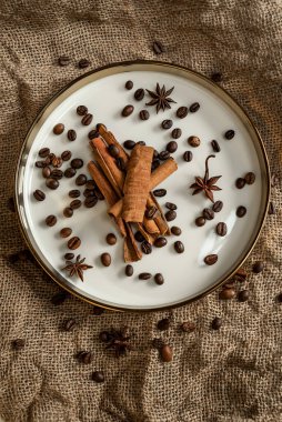 Altın bir tabakta tarçın ve anason, kahve çekirdekleri ve çuval bezi. Sert doku ve baharat kompozisyonu. Kurumuş çiçeklerle. Şekerleme, fırın ve Noel kartlarında kullanılıyor.