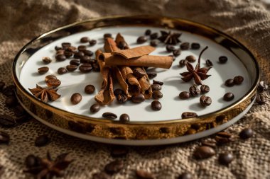 Altın bir tabakta tarçın ve anason, kahve çekirdekleri ve çuval bezi. Sert doku ve baharat kompozisyonu. Kurumuş çiçeklerle. Şekerleme, fırın ve Noel kartlarında kullanılıyor.