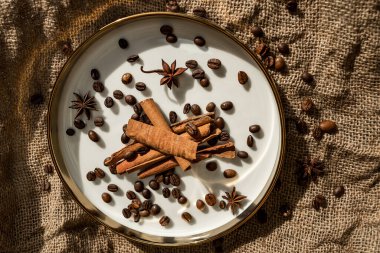 Altın bir tabakta tarçın ve anason, kahve çekirdekleri ve çuval bezi. Sert doku ve baharat kompozisyonu. Kurumuş çiçeklerle. Şekerleme, fırın ve Noel kartlarında kullanılıyor.