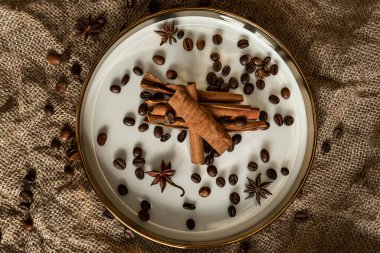 Altın bir tabakta tarçın ve anason, kahve çekirdekleri ve çuval bezi. Sert doku ve baharat kompozisyonu. Kurumuş çiçeklerle. Şekerleme, fırın ve Noel kartlarında kullanılıyor.