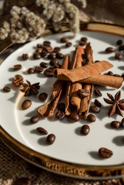 Altın bir tabakta tarçın ve anason, kahve çekirdekleri ve çuval bezi. Sert doku ve baharat kompozisyonu. Kurumuş çiçeklerle. Şekerleme, fırın ve Noel kartlarında kullanılıyor.