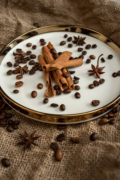 Altın bir tabakta tarçın ve anason, kahve çekirdekleri ve çuval bezi. Sert doku ve baharat kompozisyonu. Kurumuş çiçeklerle. Şekerleme, fırın ve Noel kartlarında kullanılıyor.