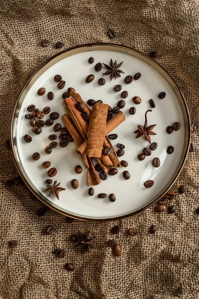 Altın bir tabakta tarçın ve anason, kahve çekirdekleri ve çuval bezi. Sert doku ve baharat kompozisyonu. Kurumuş çiçeklerle. Şekerleme, fırın ve Noel kartlarında kullanılıyor.